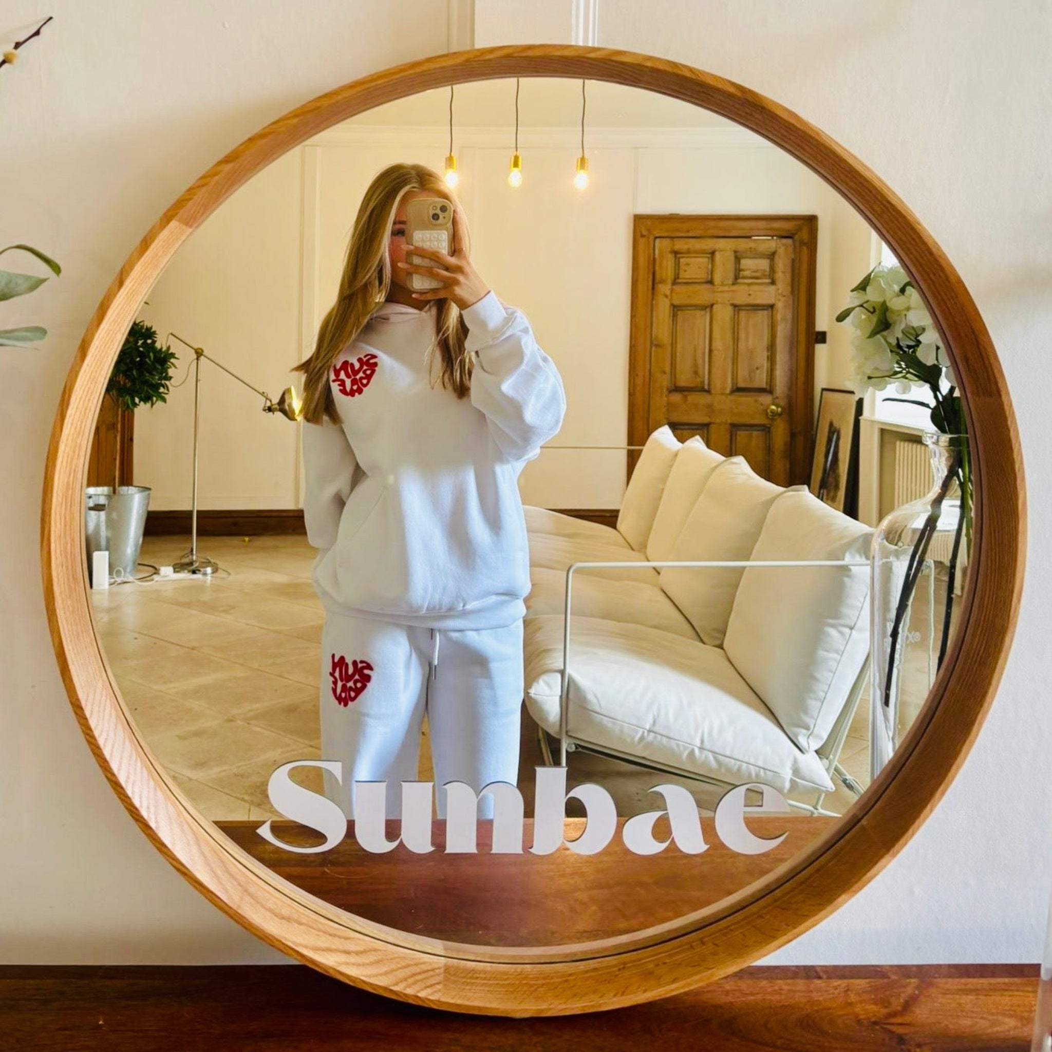 Sunbae Glower wearing Sunbae Glazed Heart Embroidery Offline Hoodie and Glow Sweat Pant, standing in a room with a round wooden-framed mirror.
