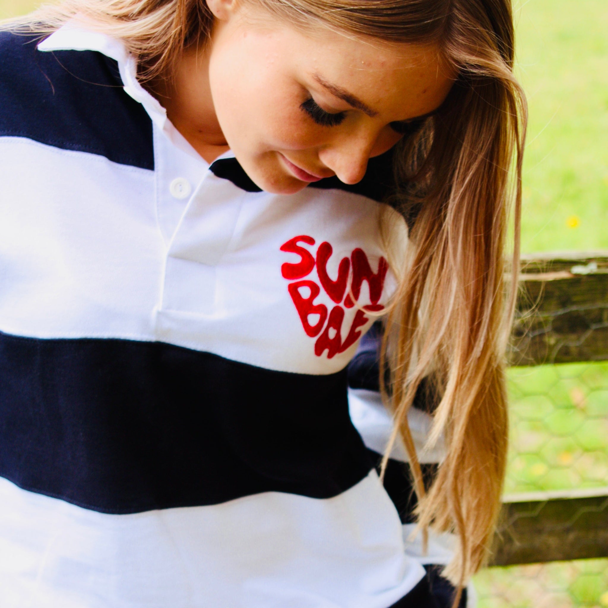 Person wearing a striped shirt with 'Sun Bum' logo outdoors