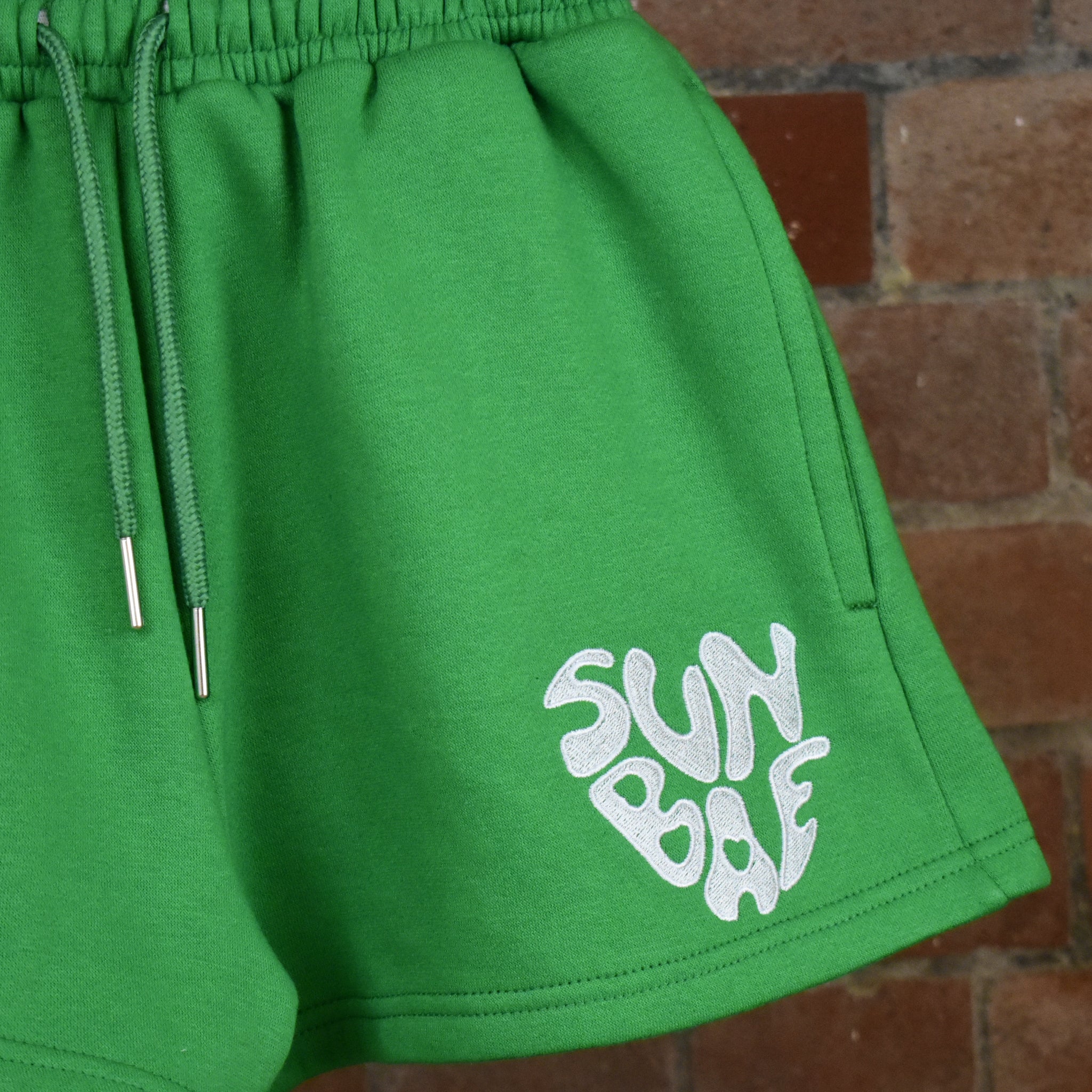 SUNBAE Green shorts on a brick wall background