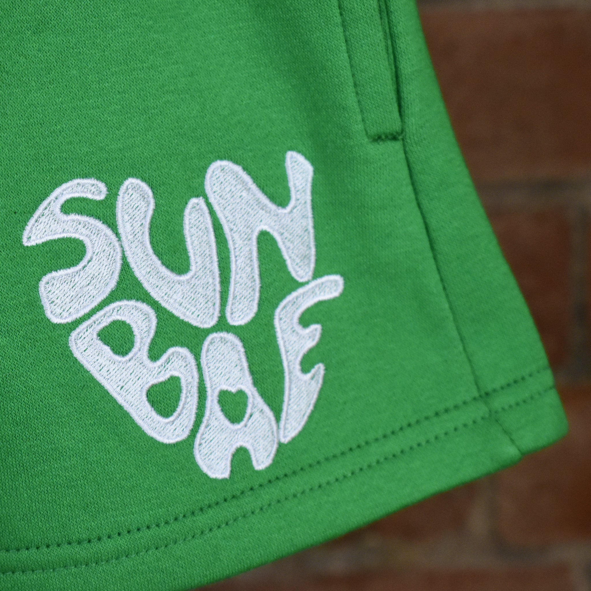 Green shorts with SUNBAE logo on a brick background