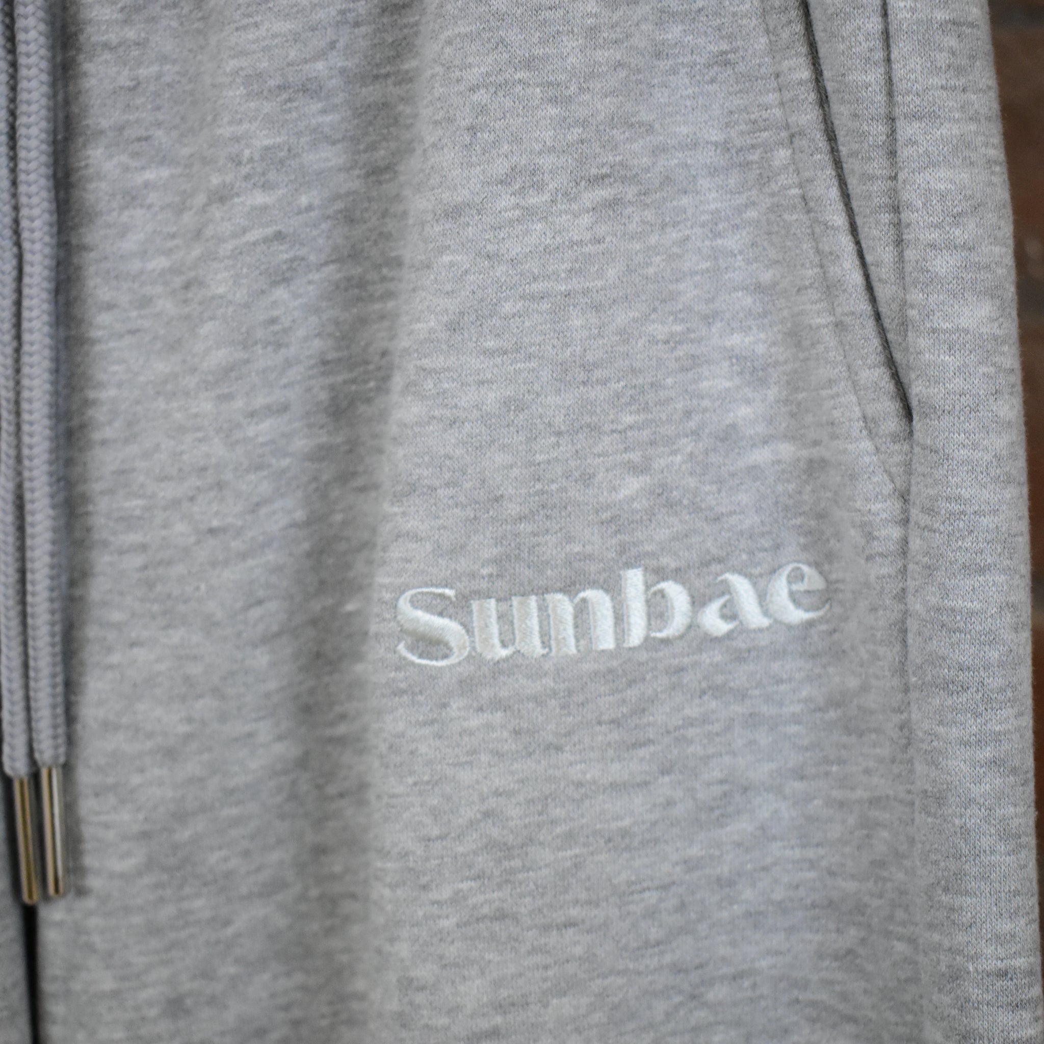 Grey ZUNBAE Sweat Pant with logo on a wooden surface