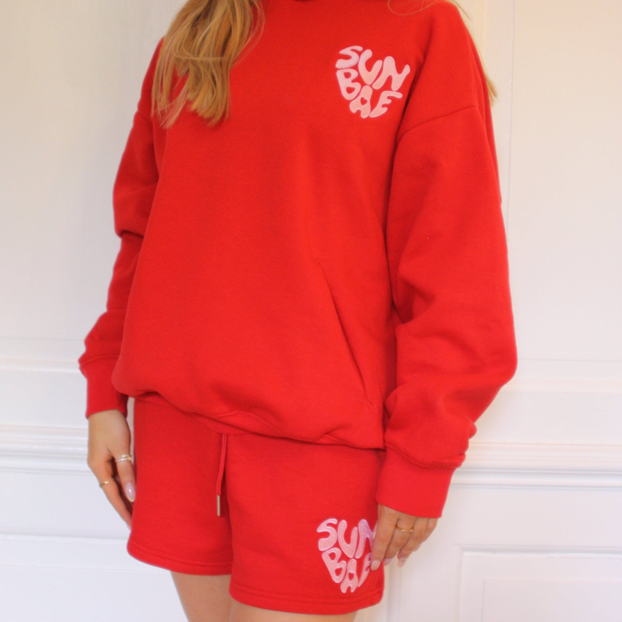 Woamn wearing a red SUNBAE Hoodie and shorts set on a white background