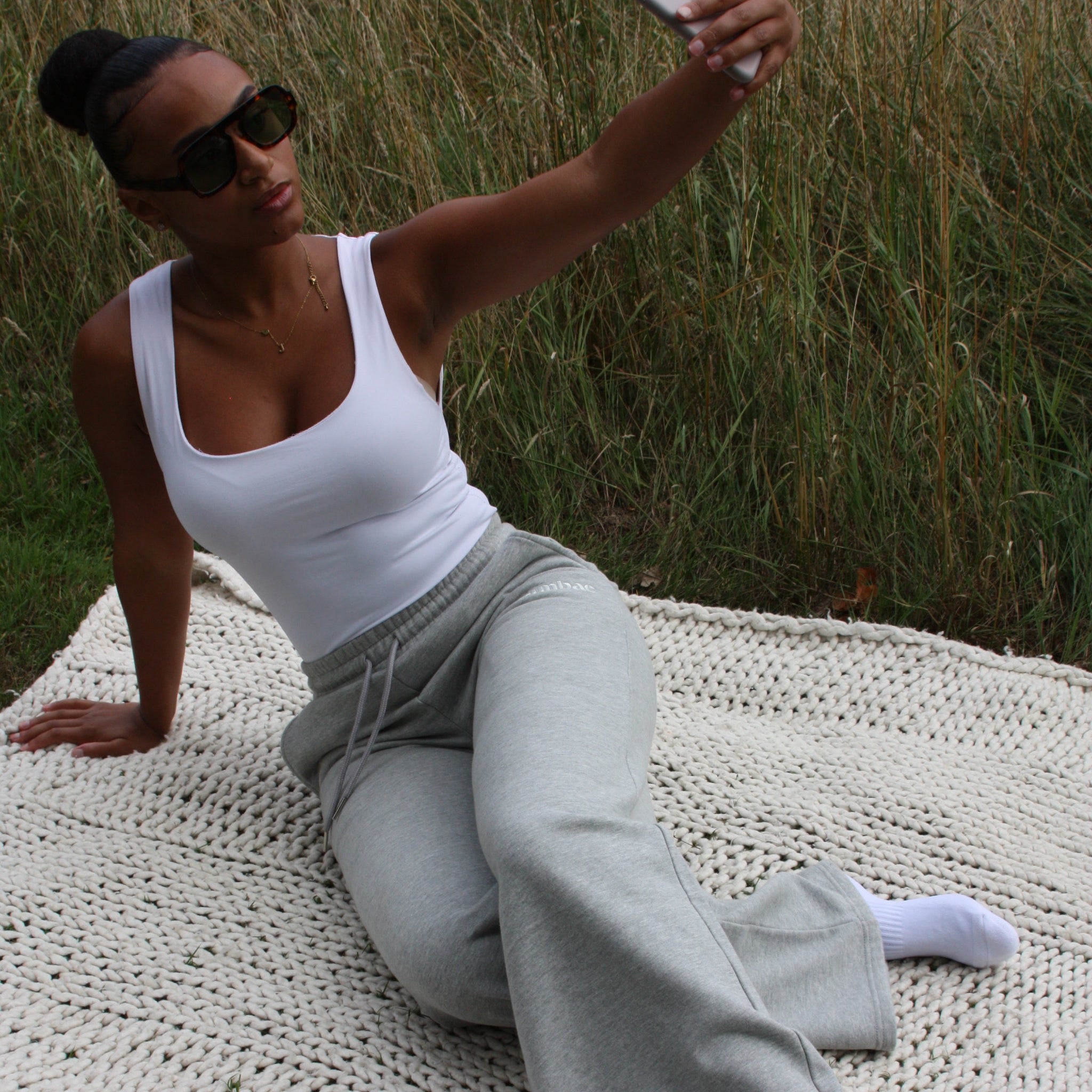 Woman wearing Sunbae sweat pants taking a selfie on a blanket outdoors