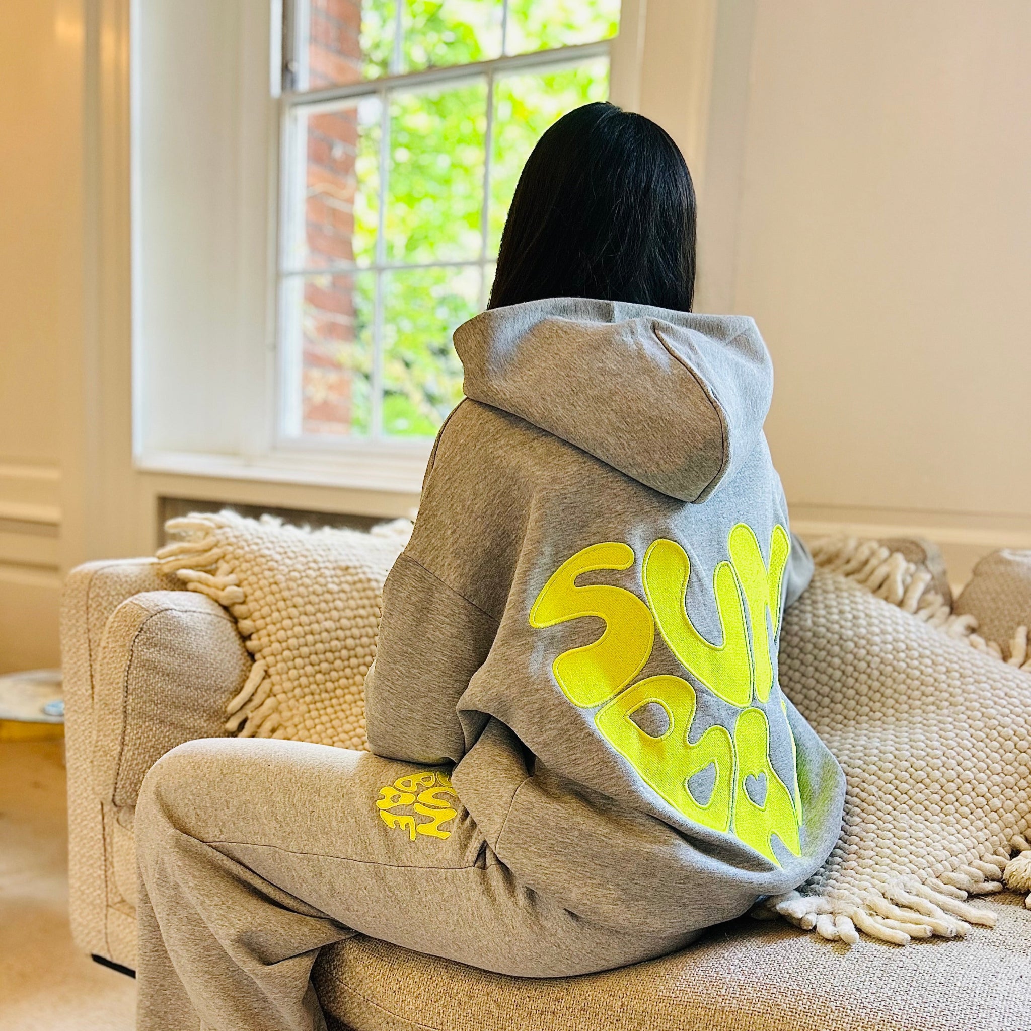 Sunbae Glower wearing a SUNBAE Offline Oversize Hoodie with Glazed Heart Embroidery in Grey Marl in a room with a window.