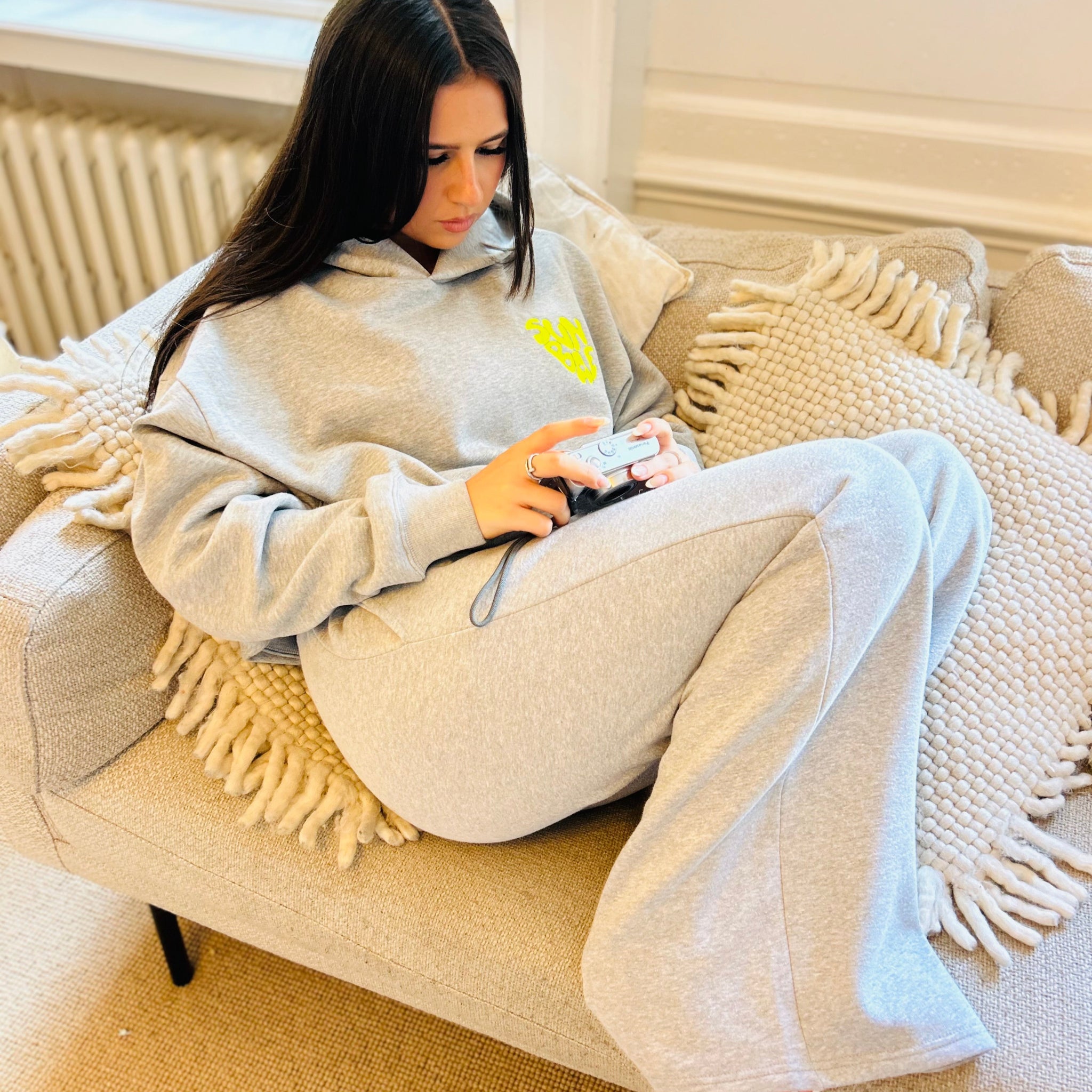 Sunbae Glower wearing SUNBAE Offline Oversize Hoodie with Glazed Heart Embroidery in Grey Marl in a cozy living room.