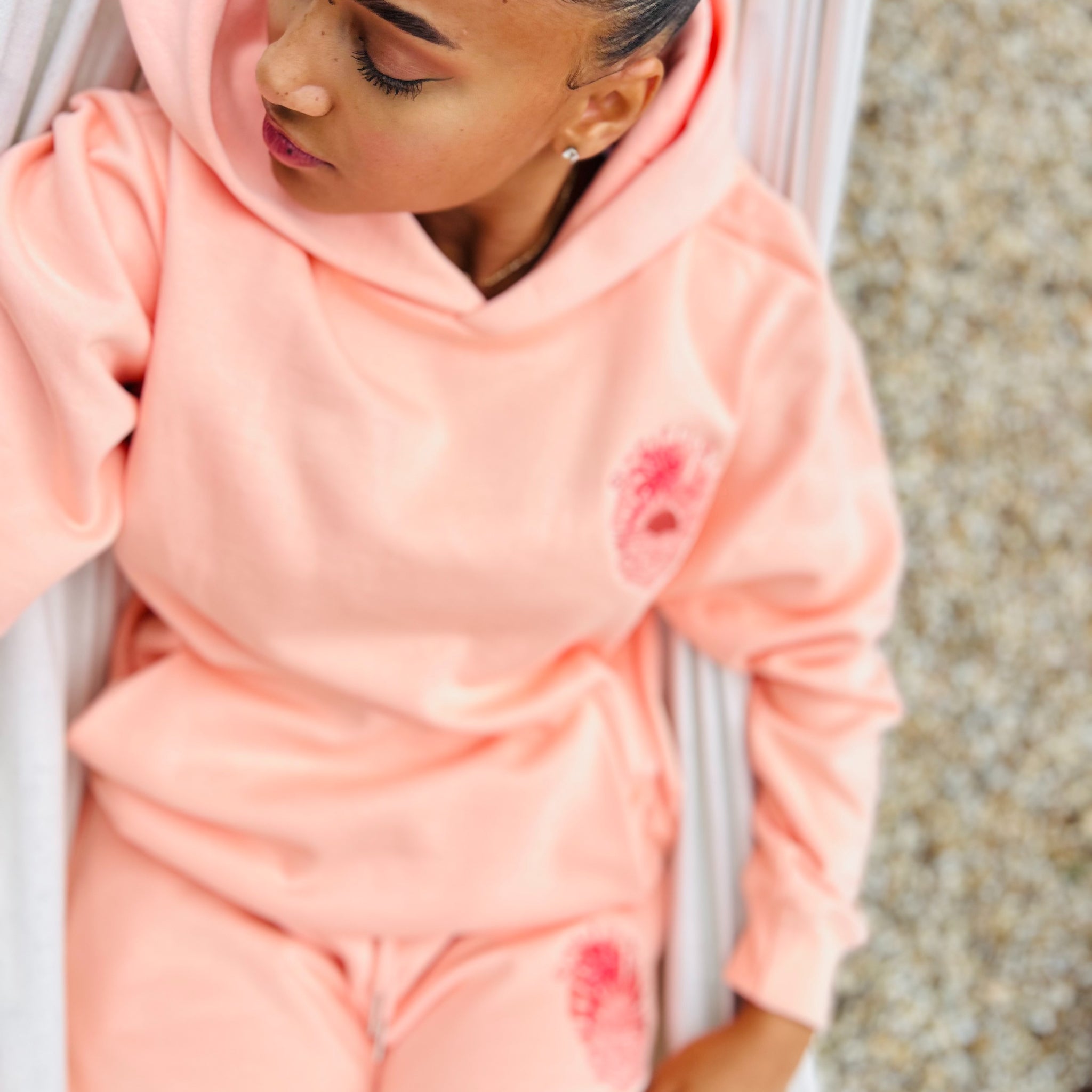 Person wearing a Coral Sunbae hoodie and Shorts on a hammock