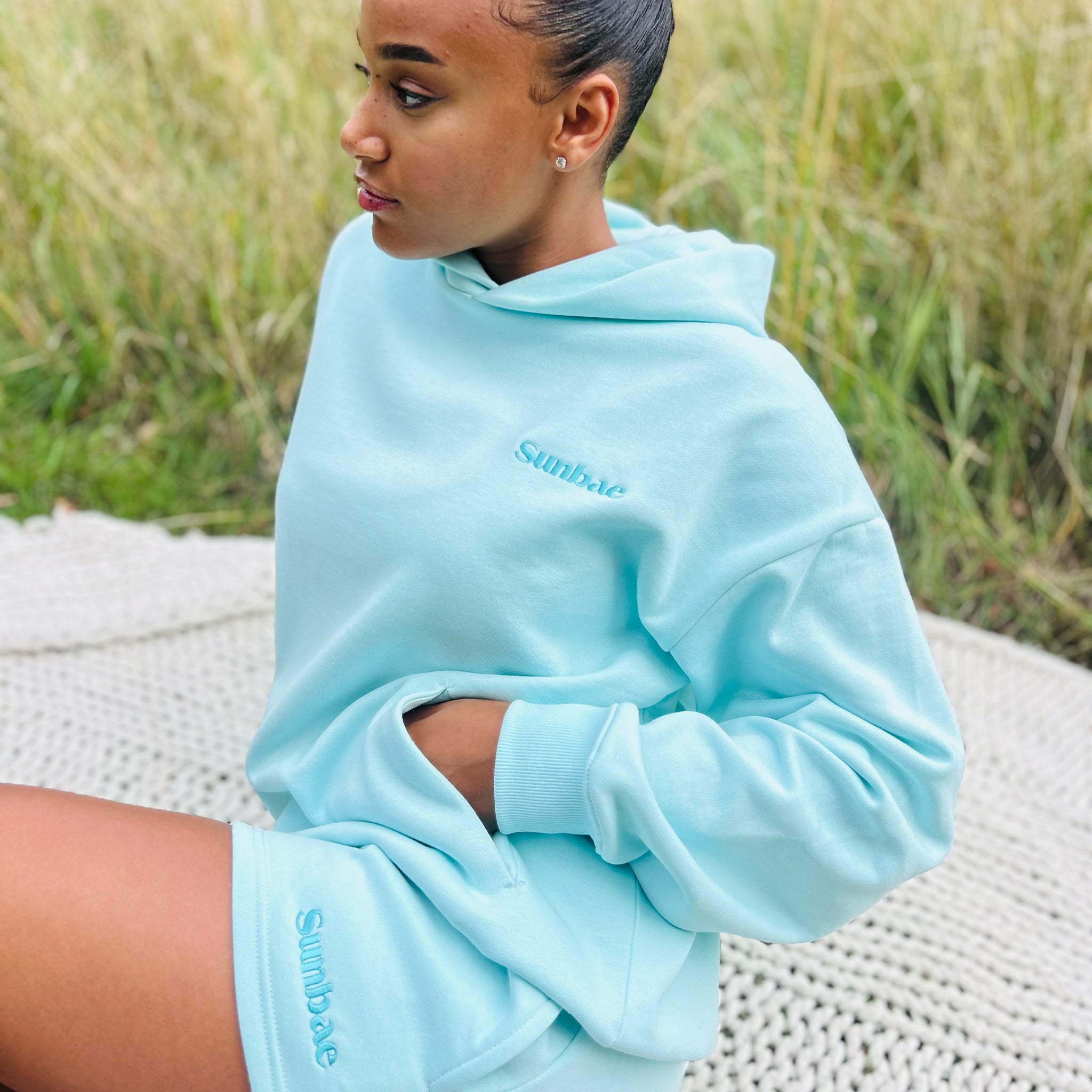 Person wearing a mint Sunbae hoodie with sitting outdoors.