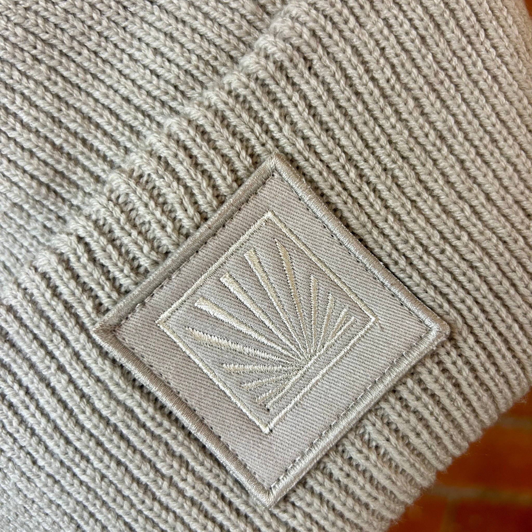 Beige textured fabric with a square patch featuring a geometric design.