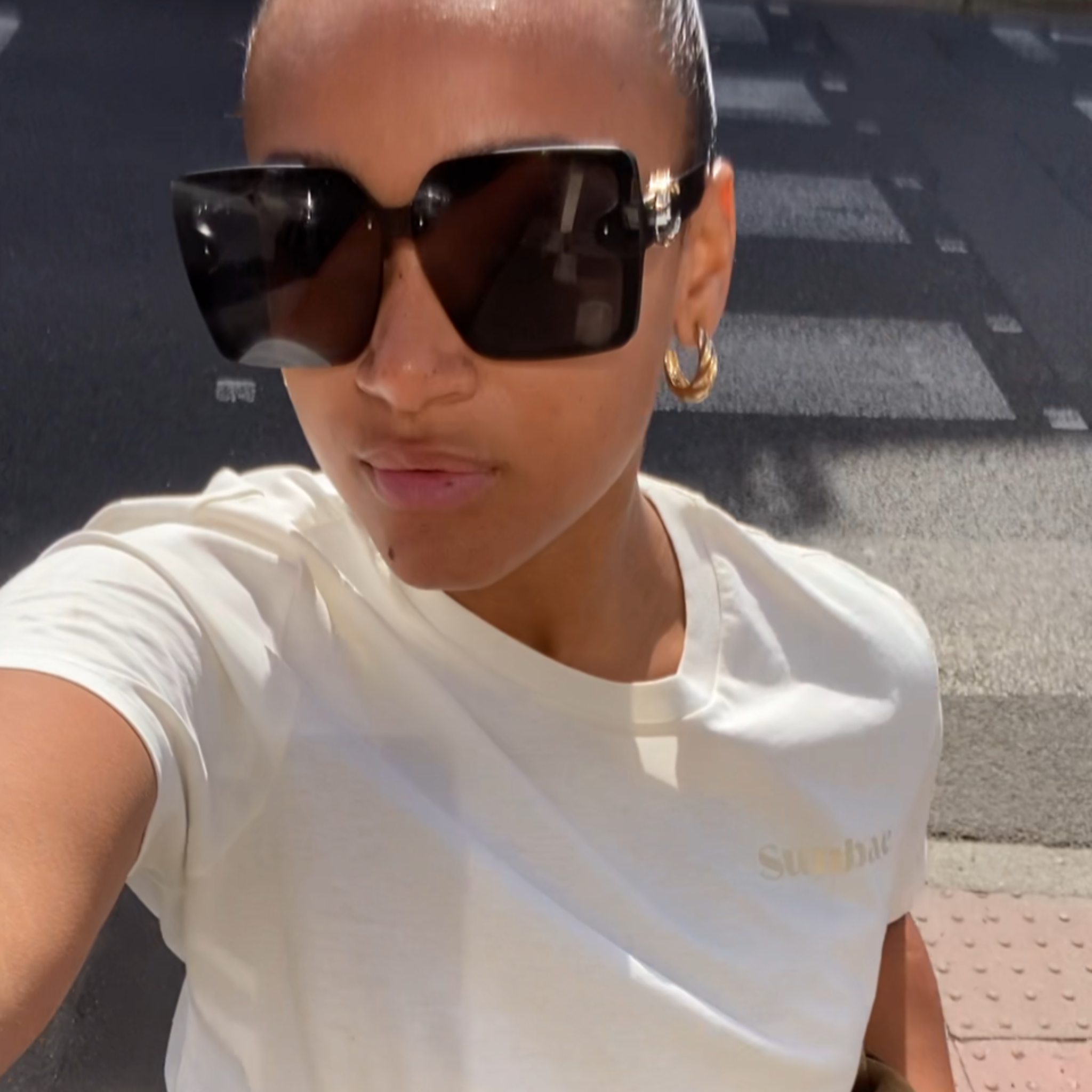 Person wearing a SUNBAE t-shirt and sunglasses on a street.