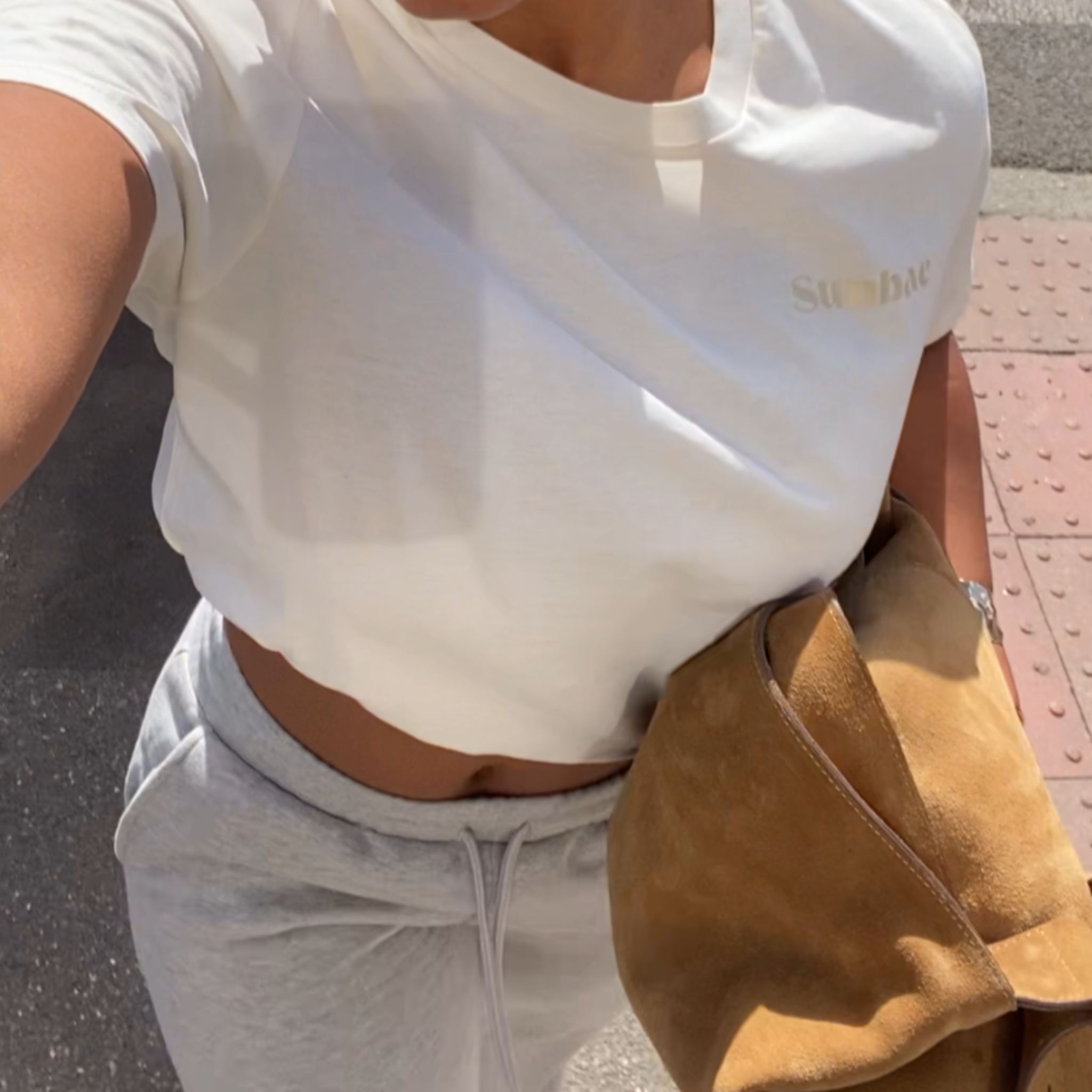 Person wearing sunglasses and a white top with a blurred background