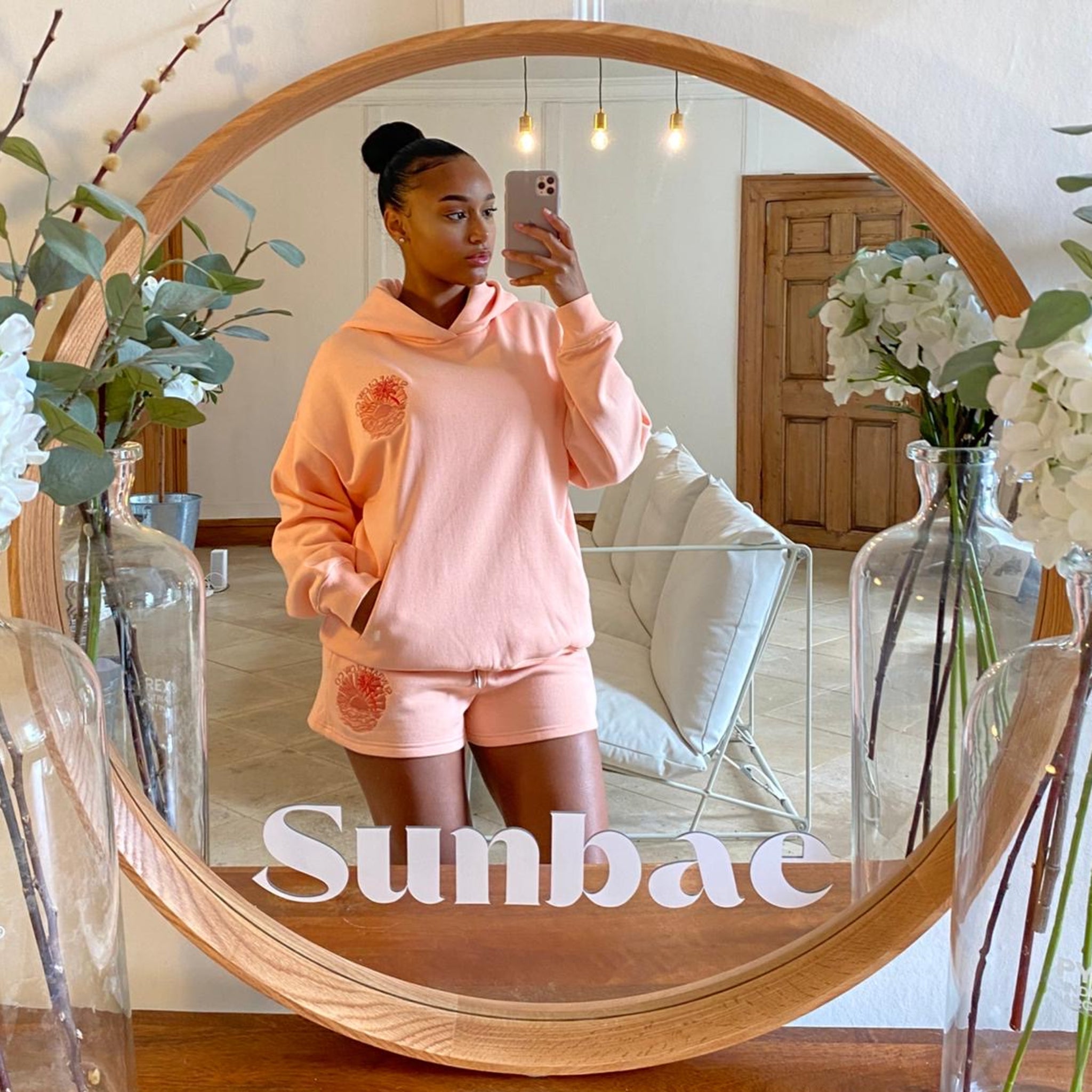Person wearing a coral outfit taking a mirror selfie with 'Sunbae' branding.