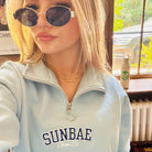 Sunbae Glower wearing  SUNBAE Cloudburst Zip Sweat with Varsity Embroidery in Blue indoors.