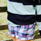 Person wearing a plaid skirt with 'Sunshine' text in front of a metal fence.