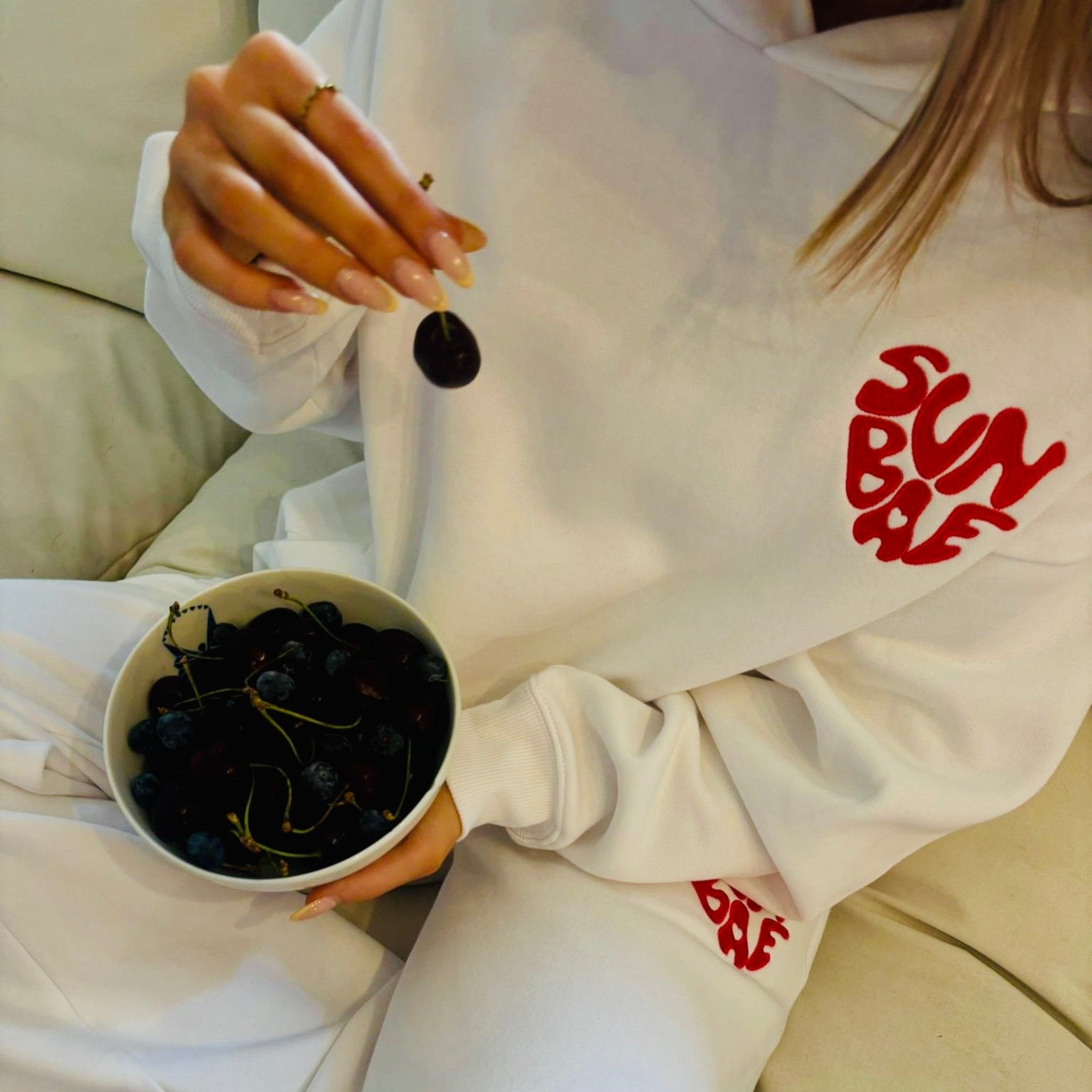Sunbae Glower wearing SUNBAE Offline Oversize Hoodie with Glazed Heart Embroidery in White holding a bowl of cherries