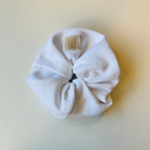 White SUNBAE scrunchie with a SUNBAE label on a light beige background.