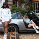 Sunbae Glow Collective wearing Sunbae Cloudburst Sweat Tops posing with a vintage car and suitcase.