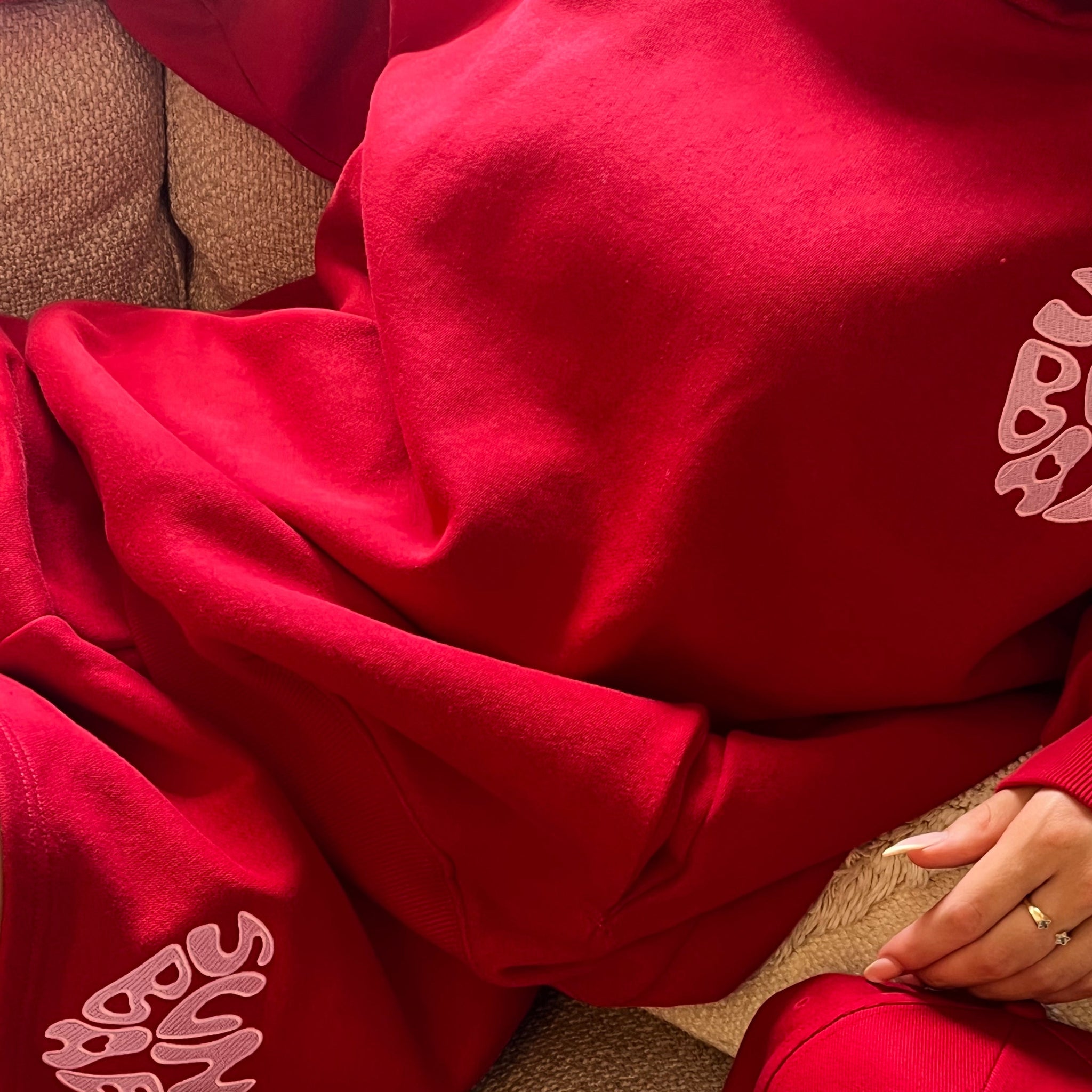 Red SUNBAE Hoodie and Short on a beige couch