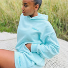 Person wearing a mint Sunbae hoodie with sitting outdoors.