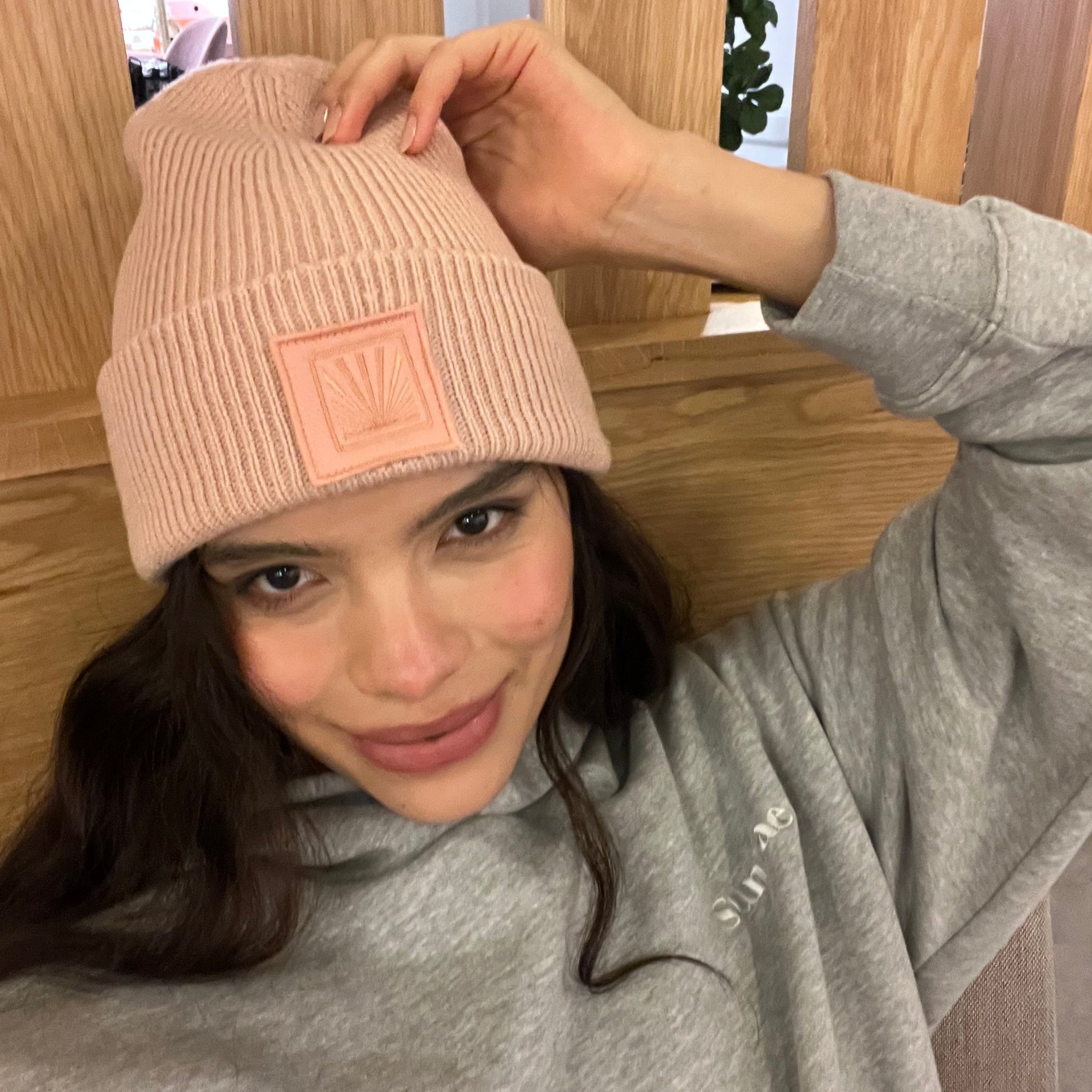 Person wearing a pink beanie with a logo, indoors.