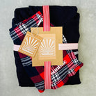 Folded black, red, and plaid fabric with Sunbac tags on a gray background