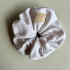 White SUNBAE scrunchie with a SUNBAE brand label on a white background.