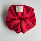 Red SUNBAE scrunchie with a SUNBAE label on a light background.
