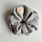 Grey SUNBAE scrunchie with a SUNBAE label on a light gray background.