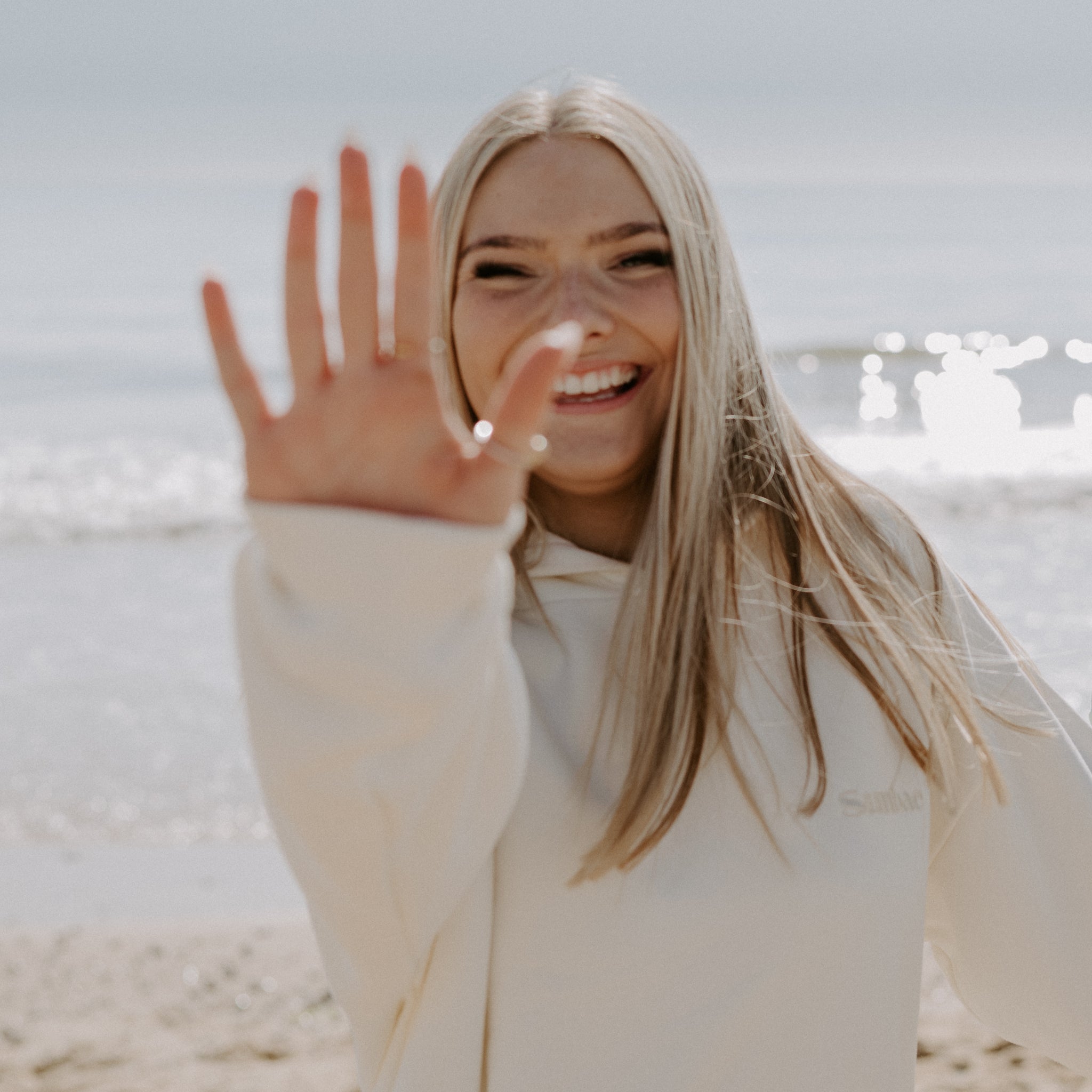 Woman waving at the camera on a beach