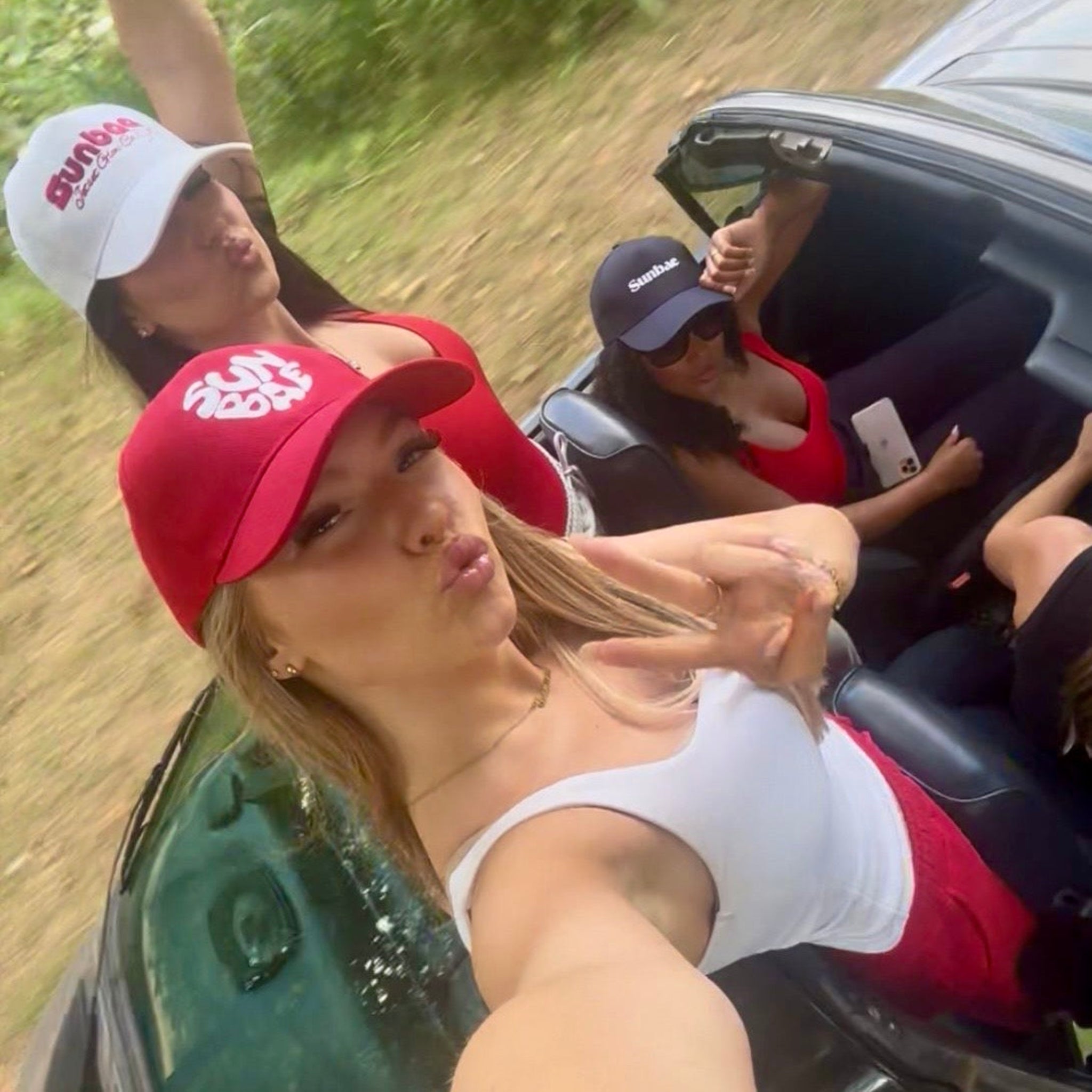 Sunbae Glow Collective wearing Sunbae Solar Caps taking a selfie in a car 
