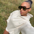 Person wearing a ivory Sunbae hoodie  in a grassy field.
