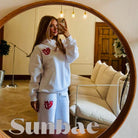 Person wearing a white outfit with red logo in front of a round mirror, with 'Sunbae' branding.